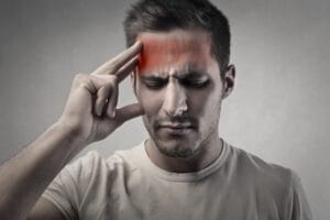 A concerned man holds his head, possibly experiencing symptoms of a mild concussion