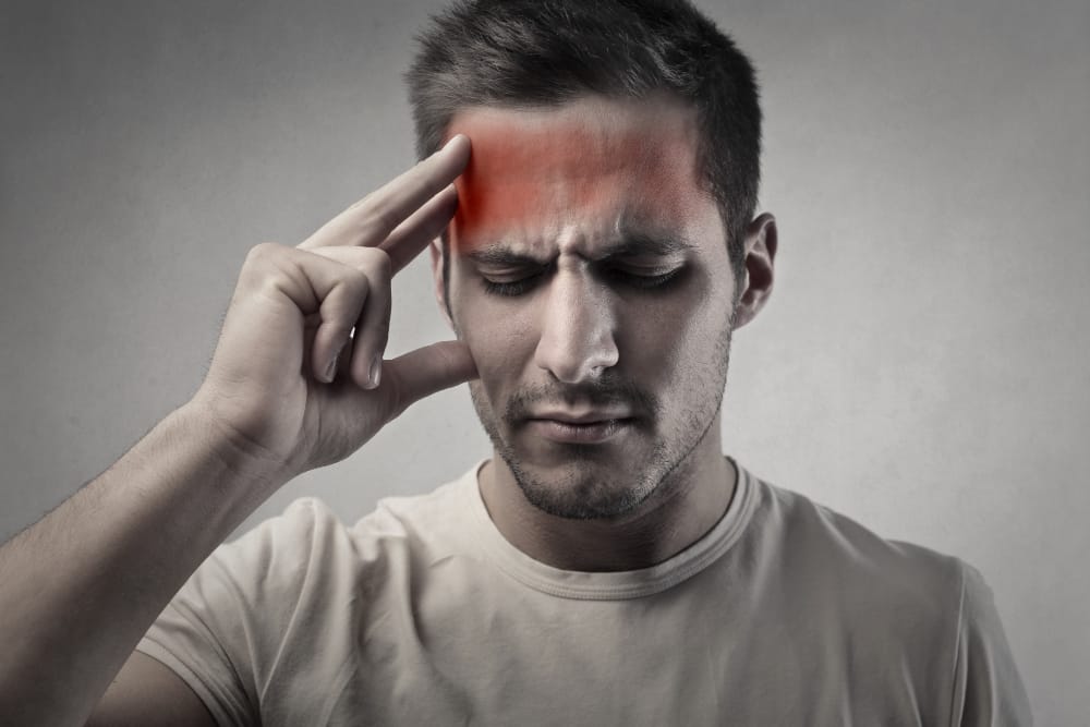 A concerned man holds his head, possibly experiencing symptoms of a mild concussion