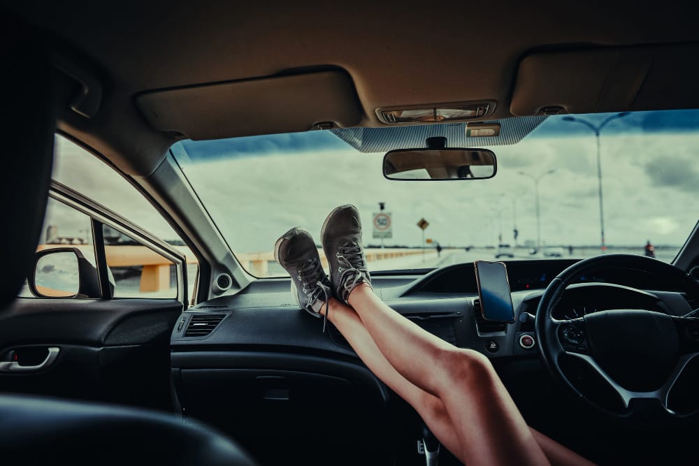 Driver's feet resting on the dashboard of a car, highlighting the dangerous practice of distracted driving.