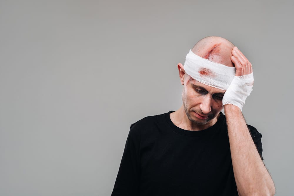 A person struggling with memory problems while holding their head, symbolizing the cognitive difficulties experienced after a traumatic brain injury (TBI).