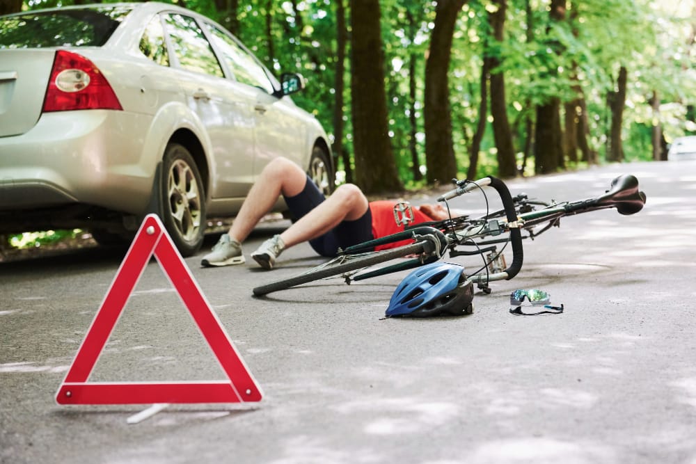 A cyclist riding on a city street, wearing a helmet and looking concerned after being hit by a car.