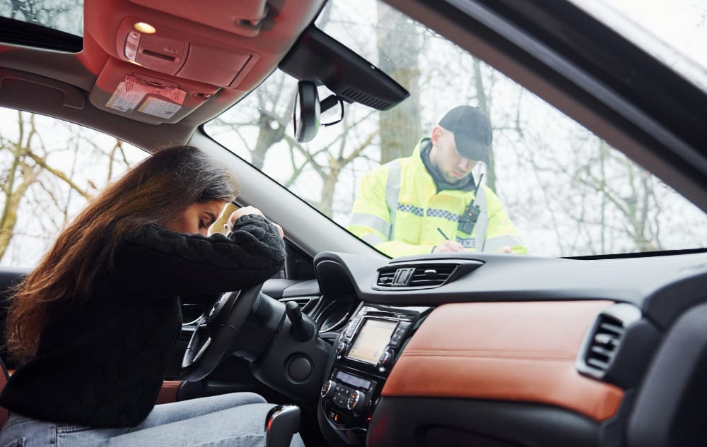 A Tesla car with its Autopilot feature engaged, parked near a road with warning signs about self-driving technology.
