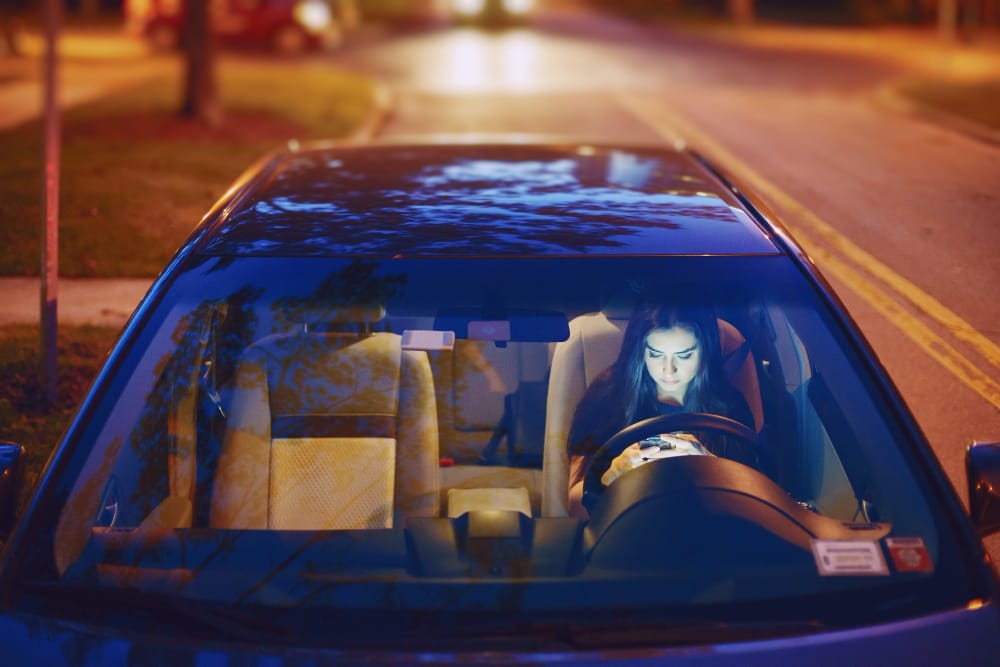 A Tesla car with its Autopilot feature engaged, parked near a road with warning signs about self-driving technology