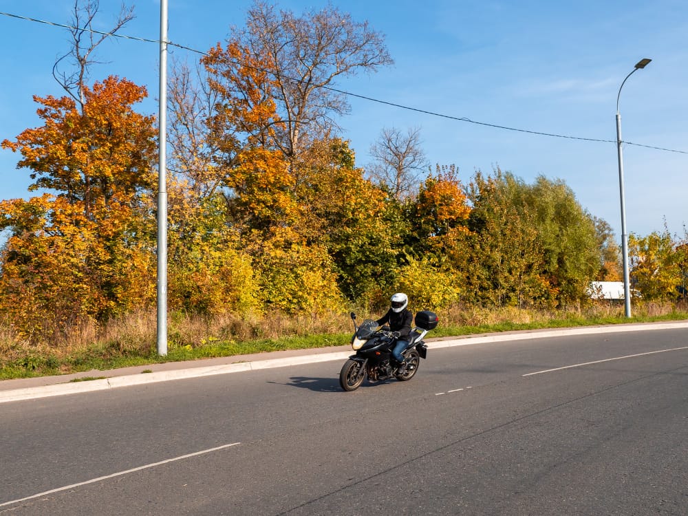 A motorcycle riding between two lanes of cars in heavy traffic.