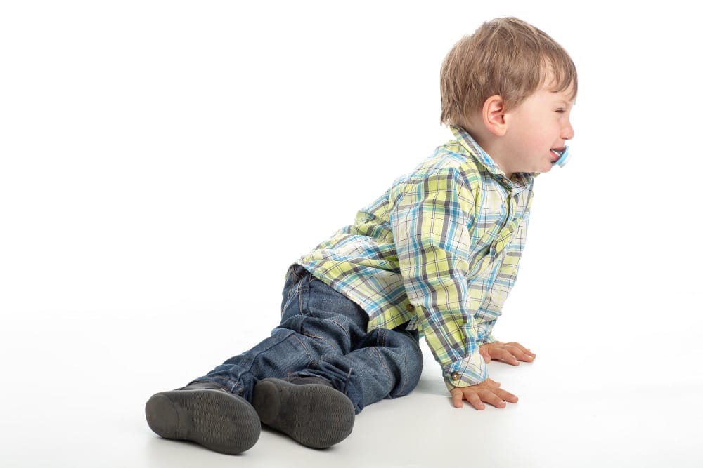 A baby lying on its back with legs bent and spread apart in a "frog leg" position.