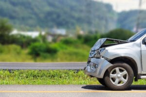 A damaged rental car on the side of the road after an accident.