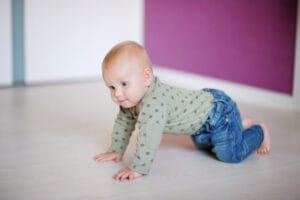 A baby lying on its back with legs bent and spread apart in a "frog leg" position.