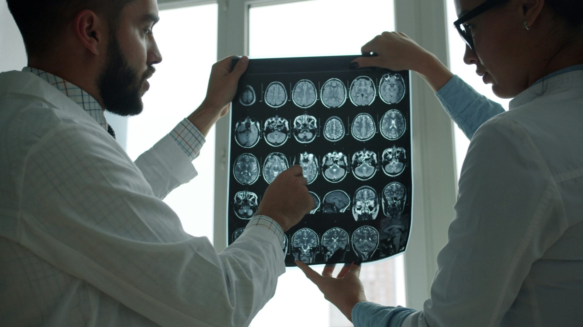 Two doctors examining brain MRI scan together discussing diagnosis