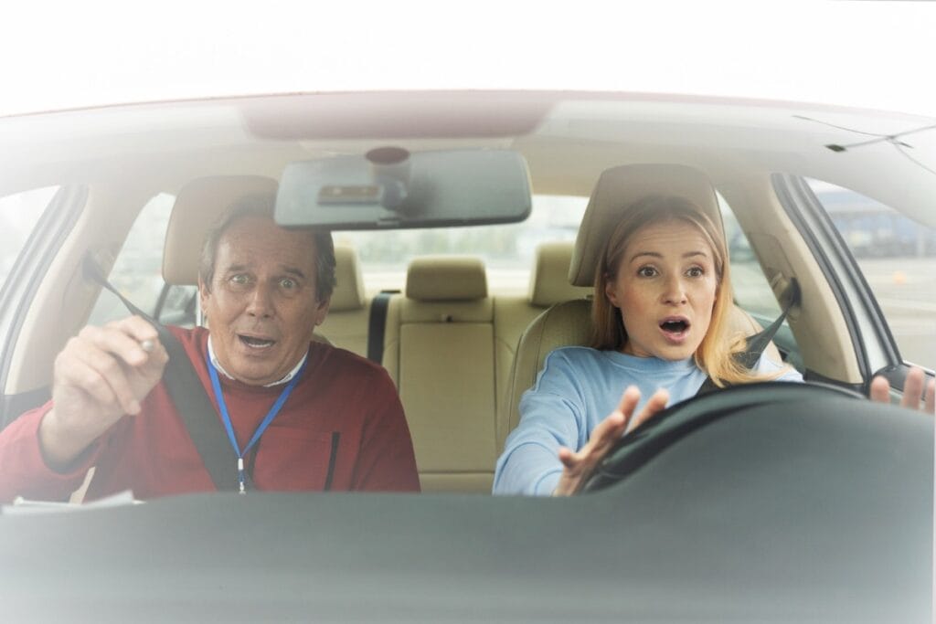 Front-seat passenger reaches for the steering wheel as another person drives, illustrating car owner liability when someone else drives your car in Illinois